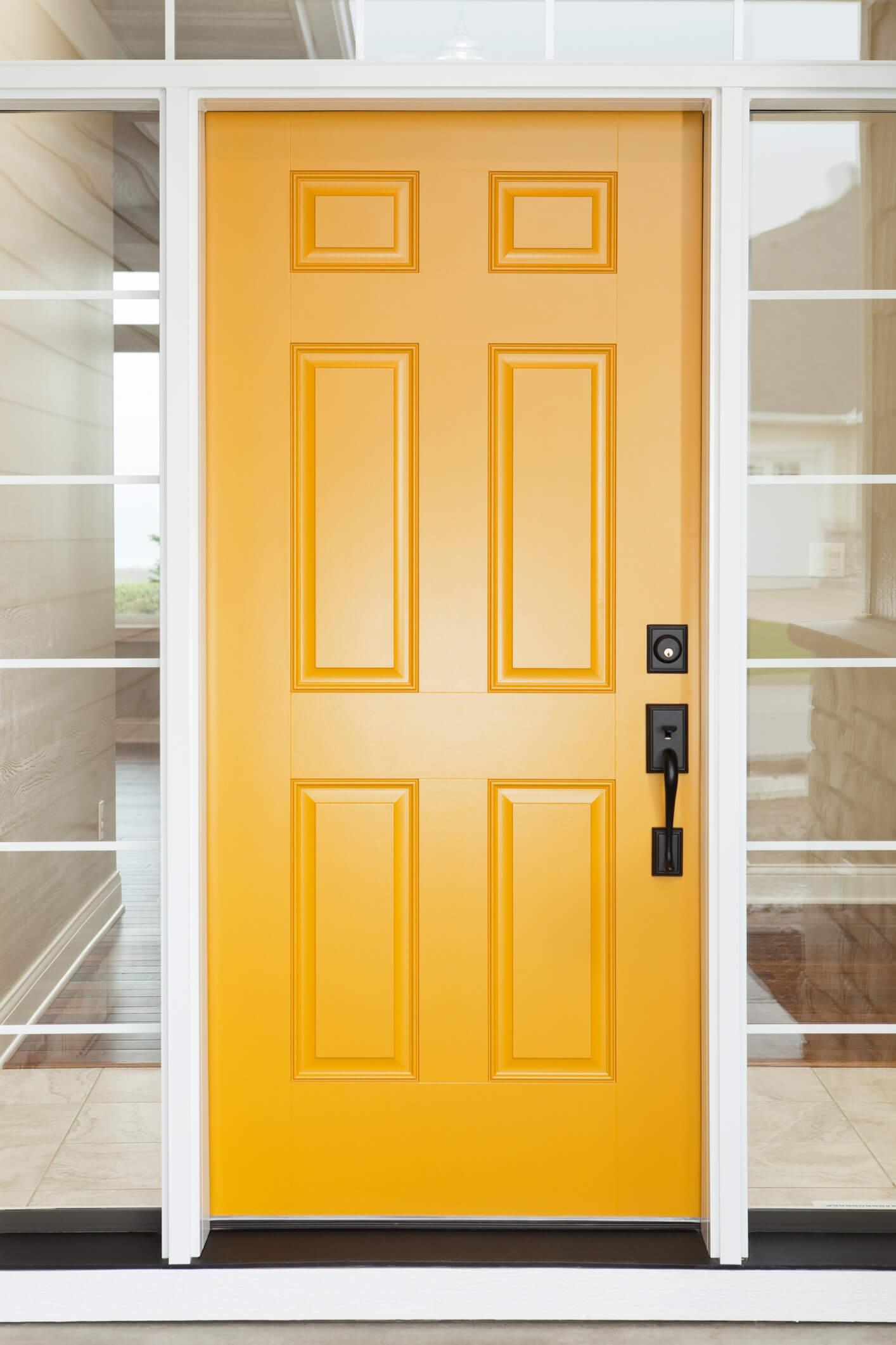 Bold yellow six-panel front door with black hardware and full-length sidelights
