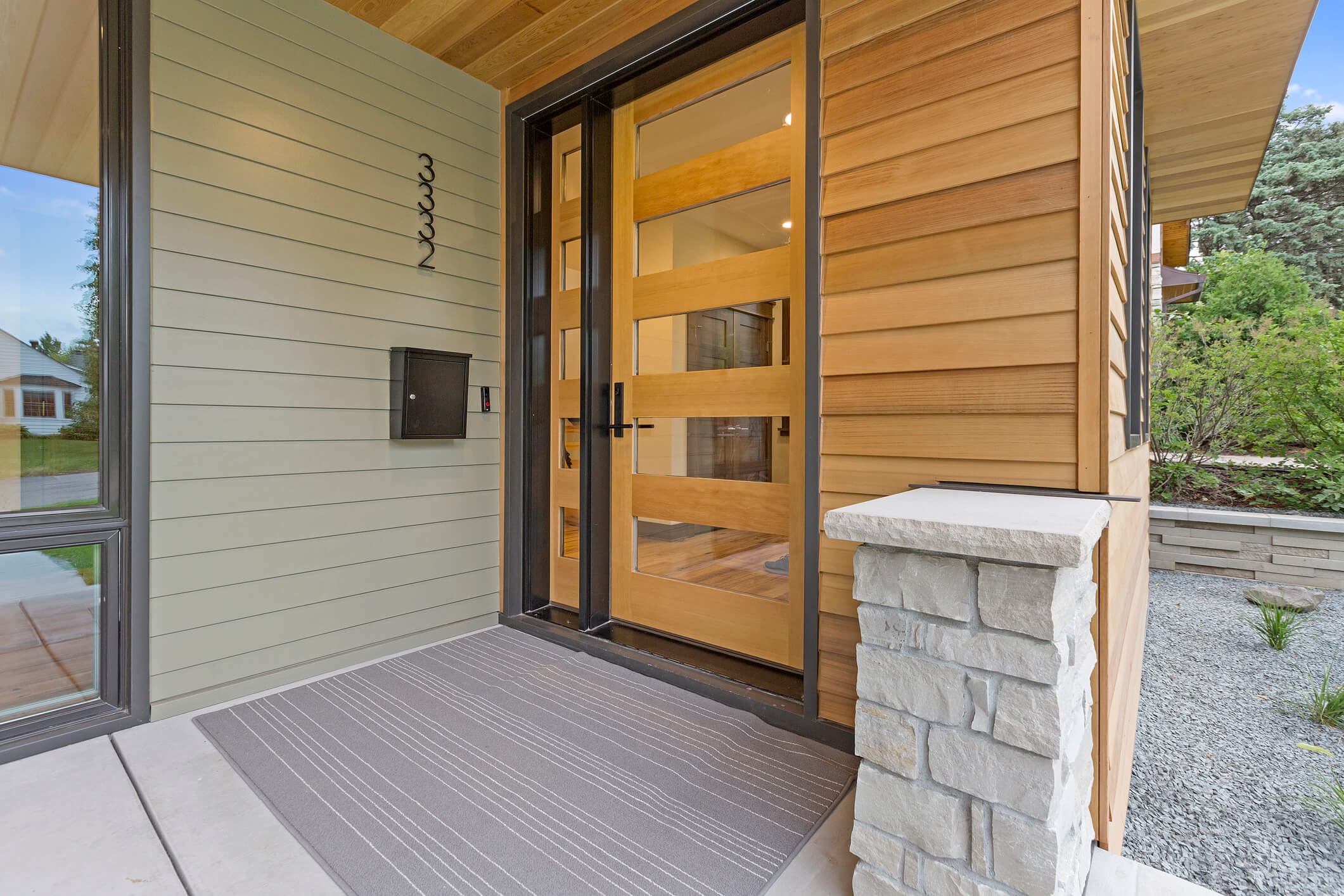 Modern wood and glass entry door with horizontal glass strips on contemporary home