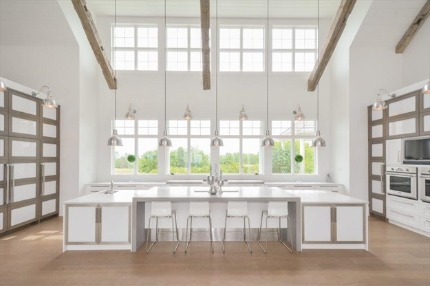 Bright white modern kitchen with tall grid windows, large island, and pendant lights