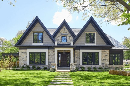 A photo of a two-story home with a black front door and black window frames.