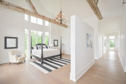Farmhouse master bedroom with vaulted beamed ceiling, four-poster bed, and French doors