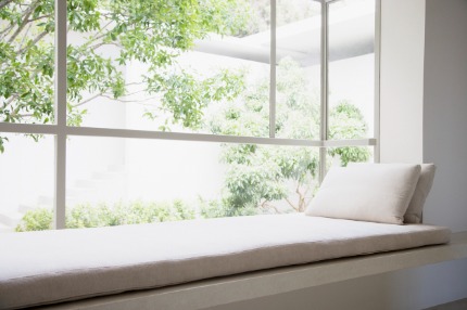 White window seat with cushion and pillow overlooking a green garden